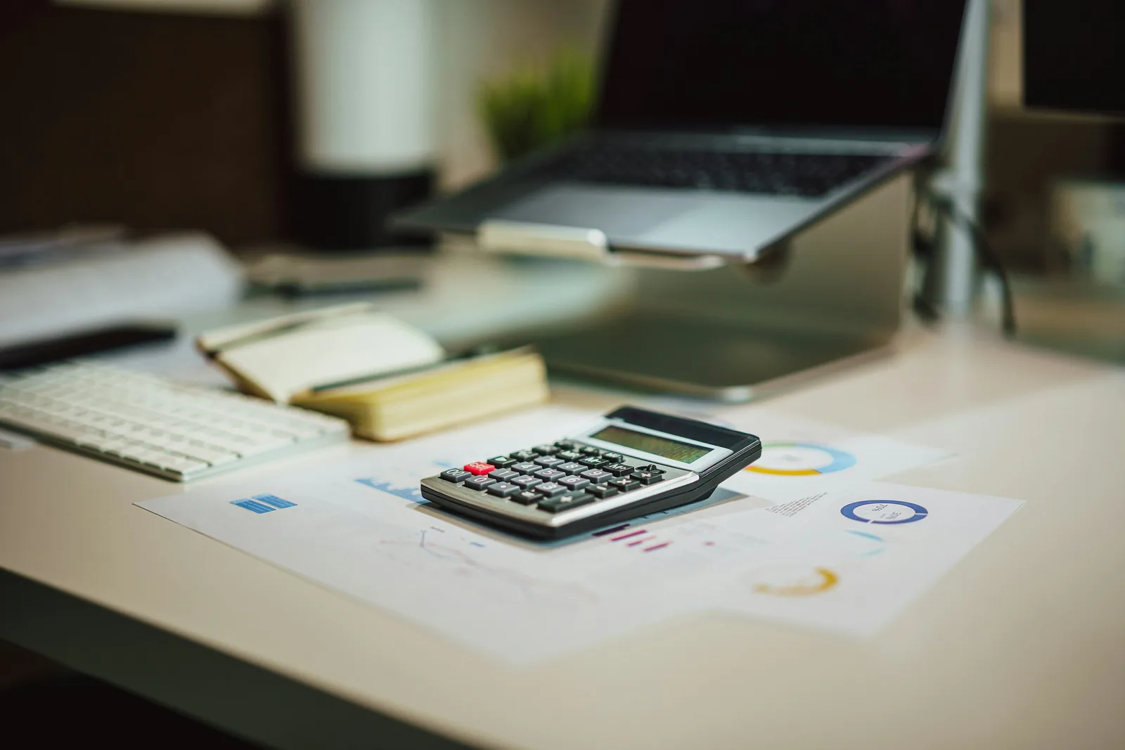 Calculadora, laptop e relatórios com gráficos sobre uma mesa de escritório